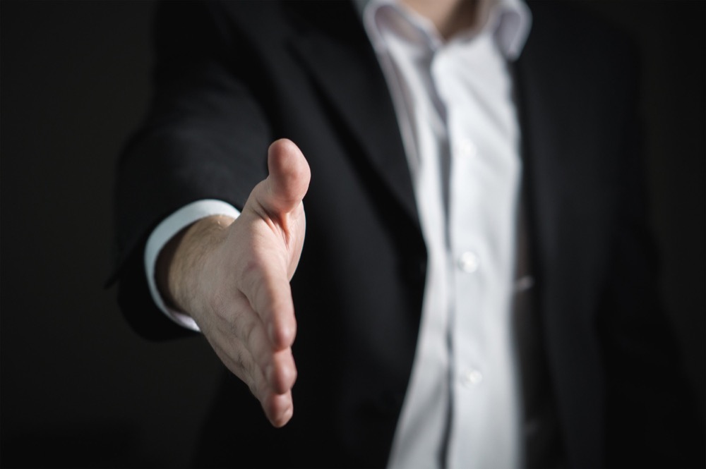 Un professionnel tend la main pour accueillir un client.